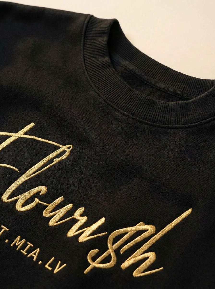Close-up of the metallic gold Flouri$h chest script and ribbed crew collar