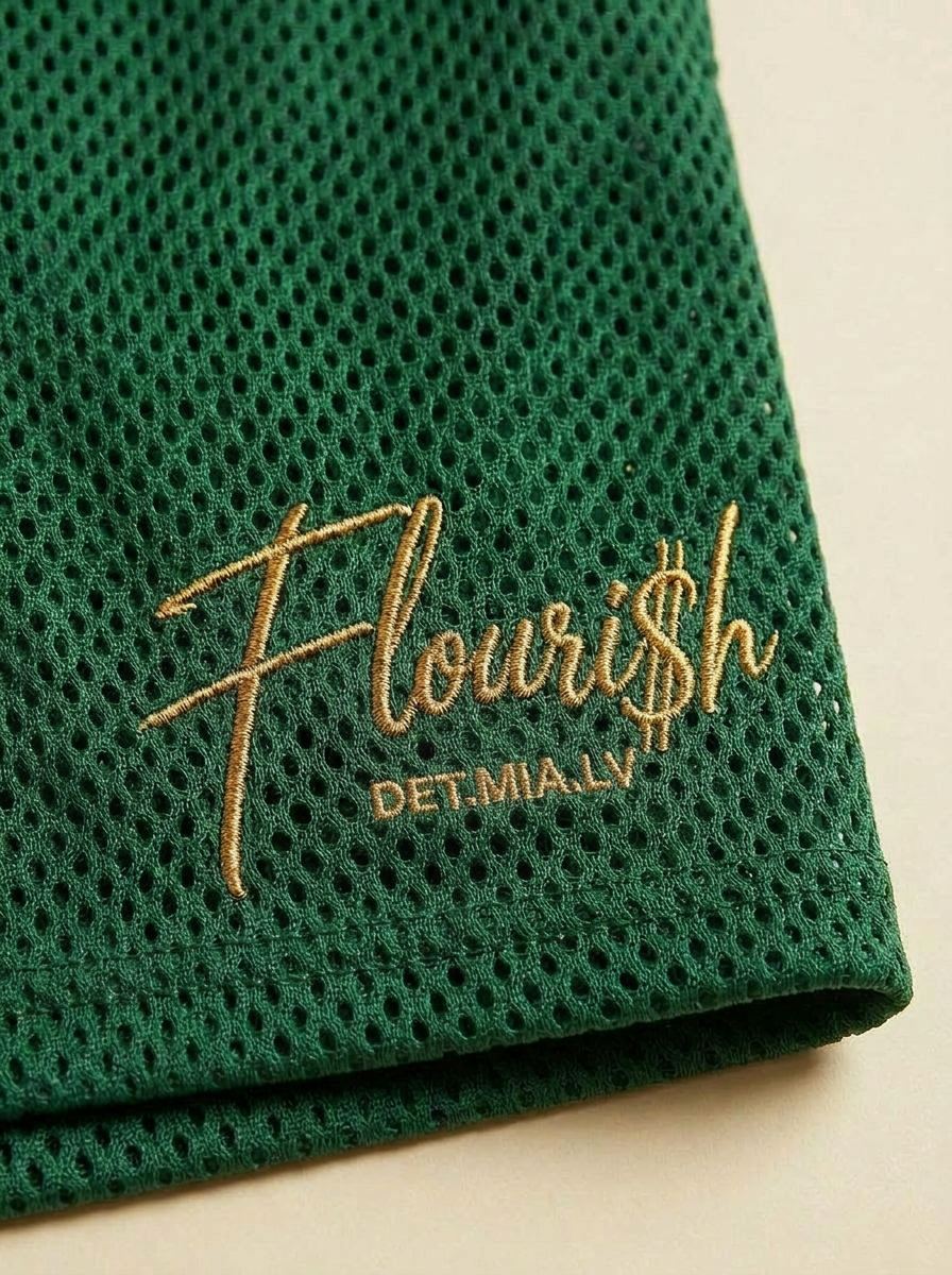 Macro close-up of the gold Flouri$h hem script on the breathable mesh short