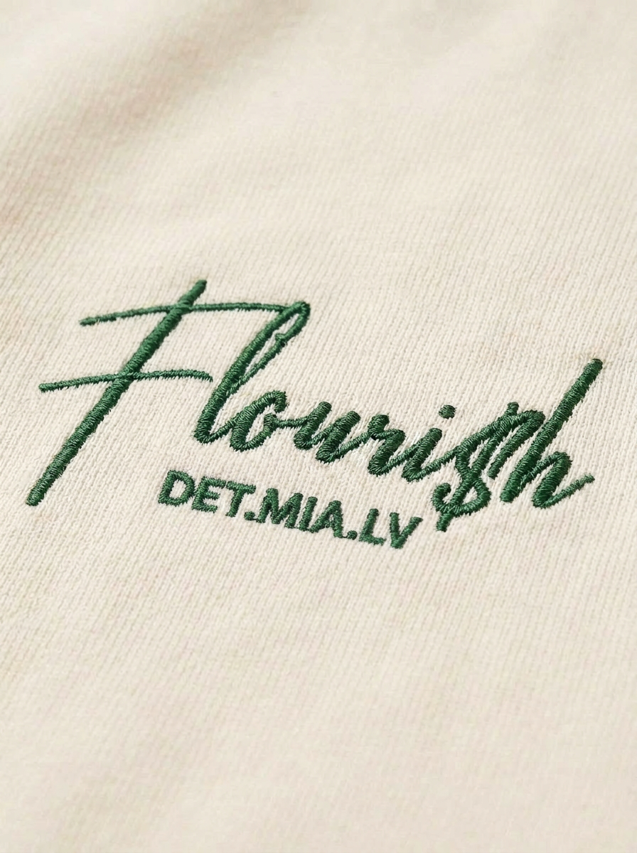 Macro close-up of the forest green Flouri$h chest script on the tee