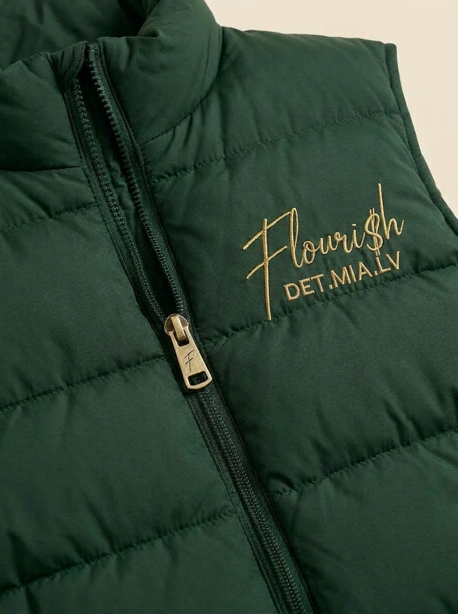 Detail of the Flouri$h Puffer Vest quilted baffles, zipper pull, and gold chest script